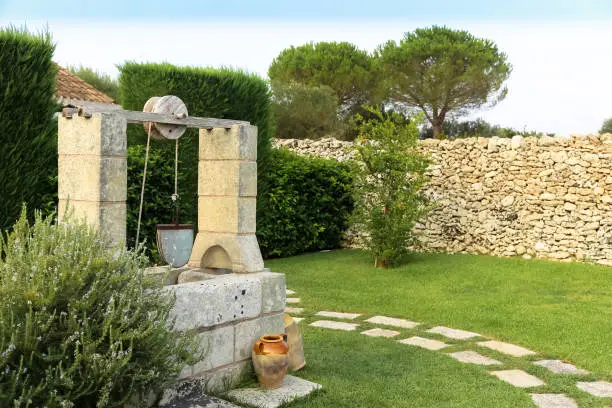 Summer season in Italy. Desing water well in an elegant garden.