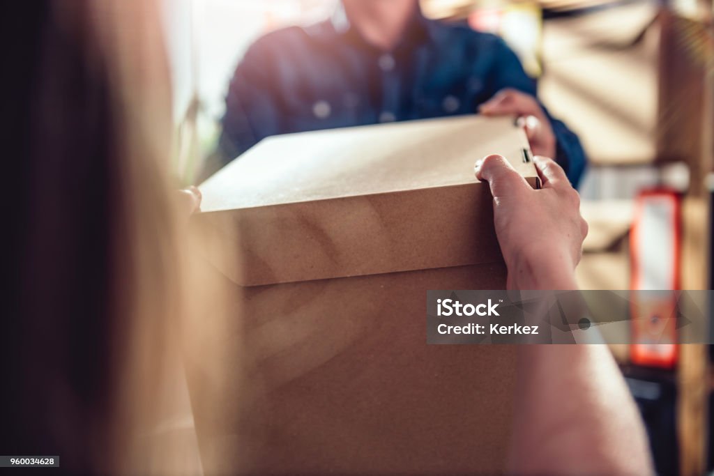 Men receiving package from courier Men wearing blue jean shirt receiving package from courier at the office Box - Container Stock Photo