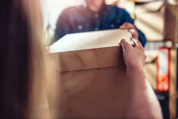 Men wearing blue jean shirt receiving package from courier at the office