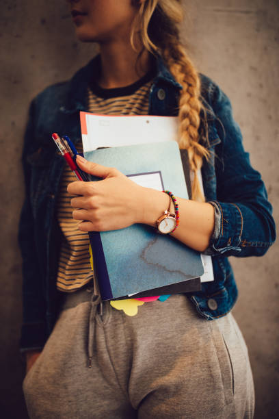istock Female college student with books and notebooks resting against wall 960035014