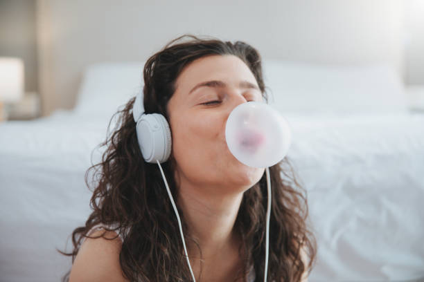young woman making a bubble from a chewing gum and listening music with headphone young woman making a bubble from a chewing gum and listening music with headphone bubble gum photos stock pictures, royalty-free photos & images