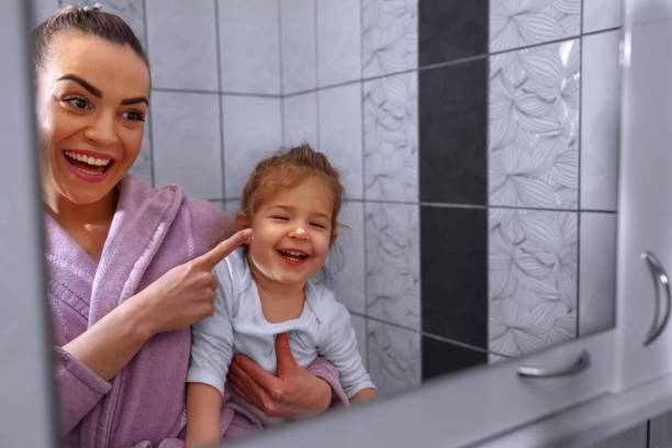 istock funny mother and daughter applying moisturizer on nose in bathroom 960039218
