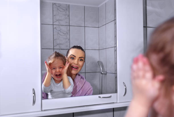 istock funny mother and daughter applying moisturizer on nose in bathroom 960039350