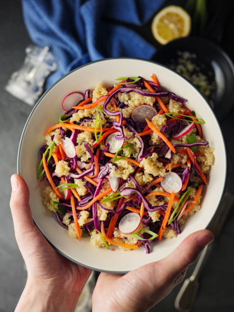 hand hold Home made freshness Asian style slaw shredded red cabbage, grated carrot, radish, spring with soy sesame dressing mix with quinoa.