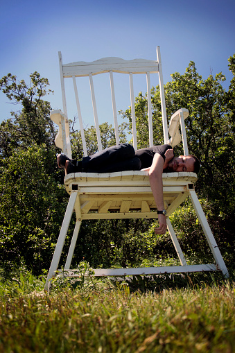 man taking a nap on over sized white rocking chair