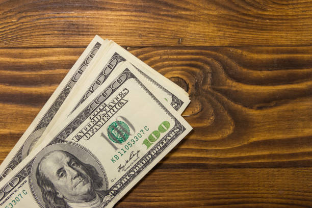istock One hundred dollars bills on wooden desk 960058136