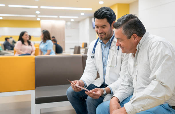 Handsome doctor talking to a male patient about a procedure showing him a brochure while talking