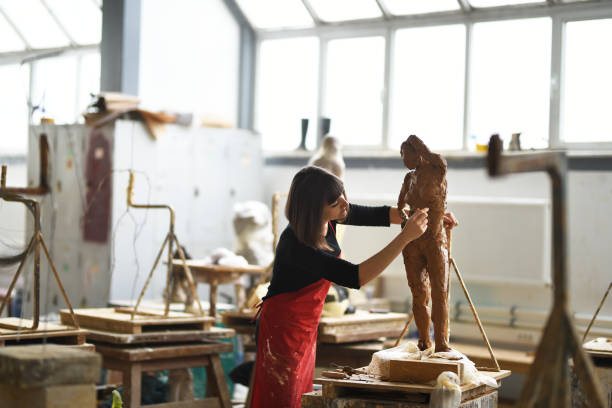 junge weibliche bildhauer arbeitet in ihrem atelier - künstlerischer beruf stock-fotos und bilder
