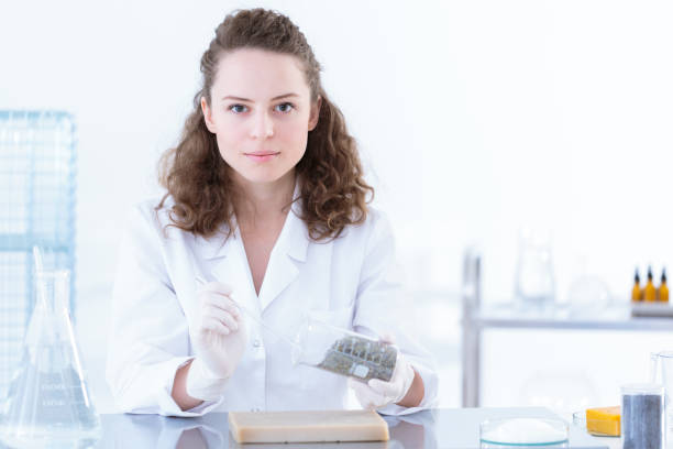 chemist woman in white uniform Portrait of chemist woman in white uniform getting a sample from beaker colloid stock pictures, royalty-free photos & images