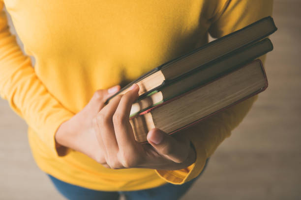 도서관에서 책을 들고 노란색 스웨터에 여성 학생의 손에 - carrying reading examining holding 뉴스 사진 이미지