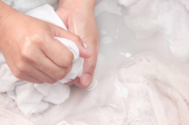 woman's hands washing white color clothes in the basin. - white clothing imagens e fotografias de stock