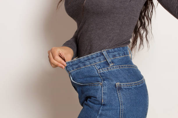 lateinische frau in baggy-hosen, drinnen. - dieting loss weight women stock-fotos und bilder
