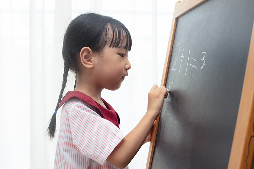 Asian Chinese little girl writing on blackboard in isolated white background