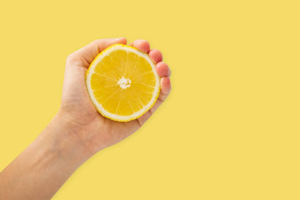 istock Female hand squeezing half of lemon on yellow background 960118016