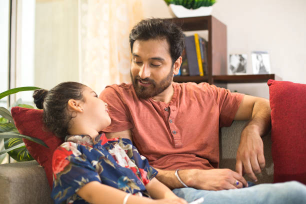 Father with daughter relaxing on sofa Father with little daughter relaxing on sofa at home parents talking to children stock pictures, royalty-free photos & images