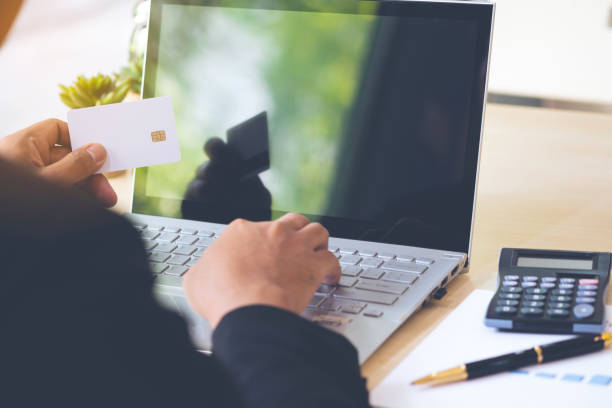 istock Businessman hand holding credit card and using laptop on desk with document and calculator. 960144270