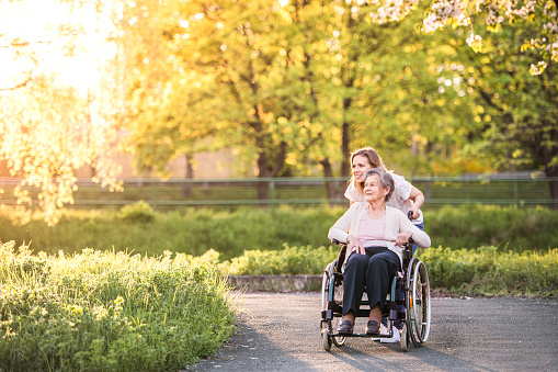 Abuela anciana en silla de ruedas con nieta en la naturaleza de la primavera. photo