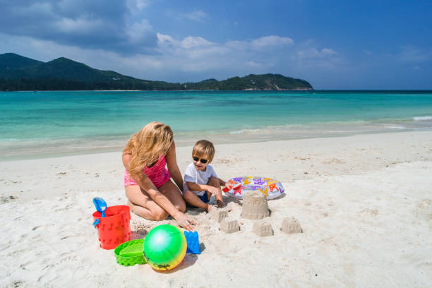 Mother and son playing with beach toys in summer day. Mother and her small son having fun while playing in sand on the beach. family beach vacations travel stock pictures, royalty-free photos & images