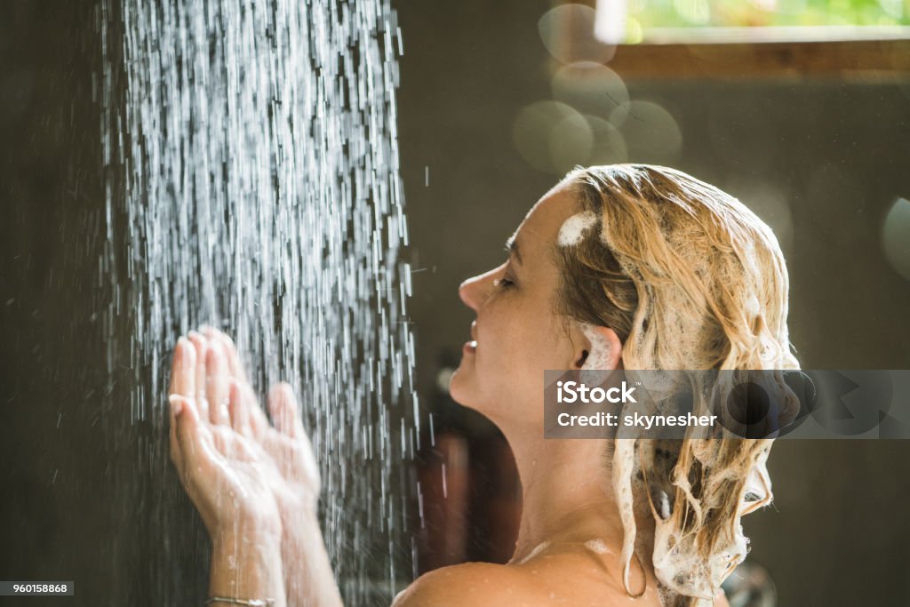 Young woman enjoying while showering in the bathroom. Woman washing her hair while showering in the morning. Washing Hair Stock Photo