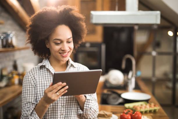 istock Happy African American woman using digital tablet in the kitchen. 960161338