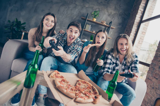 istock Who will be the winner? Four cheerful excited joyful delightful crazy gamers spending time together eating takeaway food drinking deer on couch at home 960167190