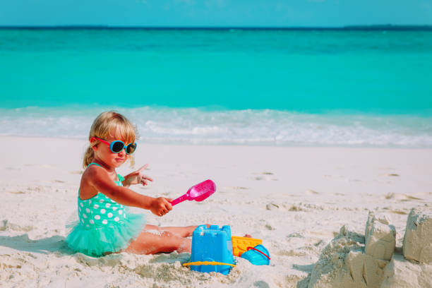 istock cute little girl play with sand on beach 960175724