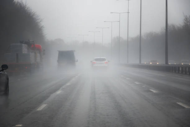 conduite sur l’autoroute à londres dans le mauvais temps - asphalt two lane highway natural phenomenon fog photos et images de collection