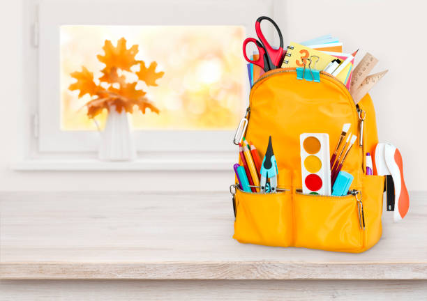 istock Yellow school bag on wooden table over autumn windowsill background 960188366