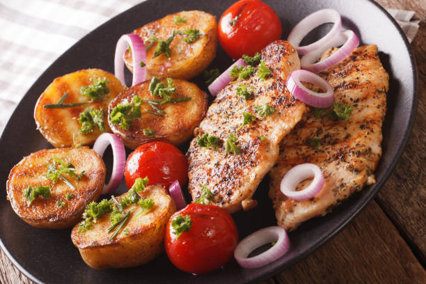 istock Delicious food: fried chicken breast with grilled potatoes and tomatoes close-up on a plate. horizontal 960195272
