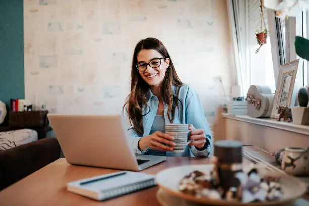 Photo of Student woman sitting at desk near window in her apartment.