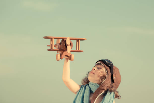 istock Happy child playing with toy airplane against summer sky 960209628