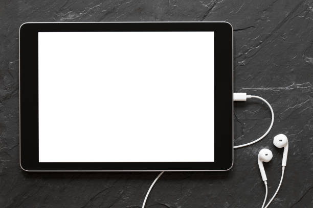 Close-up photography of tablet with empty screen and earphones on black stone surface