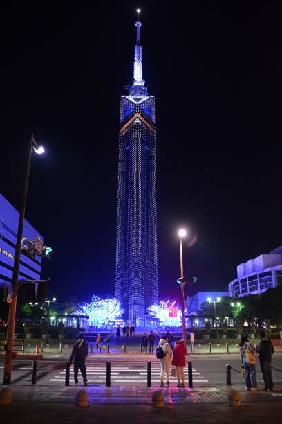 Tourists sightseeing down the beautifully lighten Fukuoka Tower by night, which stands 234 meters tall and is the city's highest building. It's located in the Momochihama area of Fukuoka, Japan