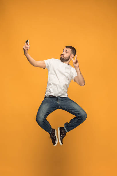 istock Time to take selfie. Full length of handsome young man taking selfie while jumping 960220840