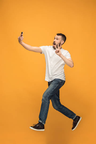 istock Time to take selfie. Full length of handsome young man taking selfie while jumping 960220962