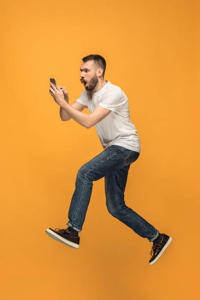 Full length of handsome young man taking selfie while jumping