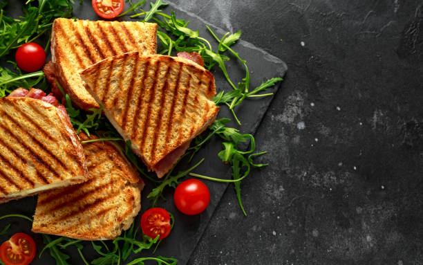 istock Grilled Bacon, cheese sandwich and served on stone platter with arugula and tomatoes 960221932