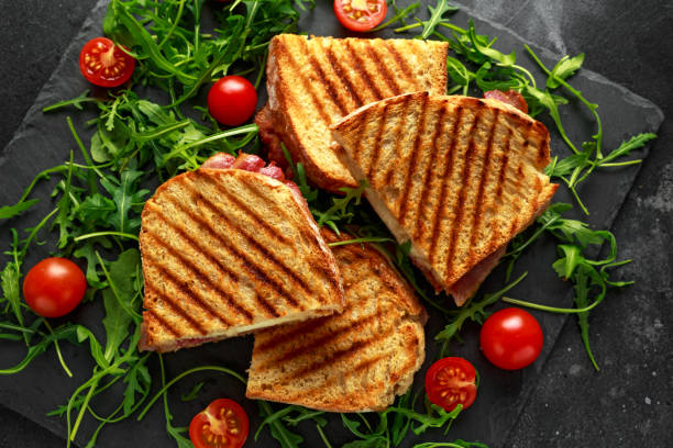 istock Grilled Bacon, cheese sandwich and served on stone platter with arugula and tomatoes 960222054
