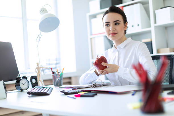 istock Young girl in the office working with documents and holding an apple. 960222576