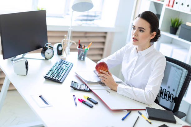 istock Young girl in the office working with documents and holding an apple. 960222580