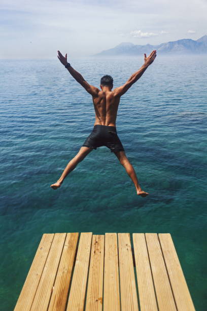 istock Young man jumping into the sea from wooden platform 960232306