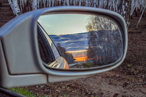 Sunset reflection in the rear view mirror of a car on a highway. Blur shot