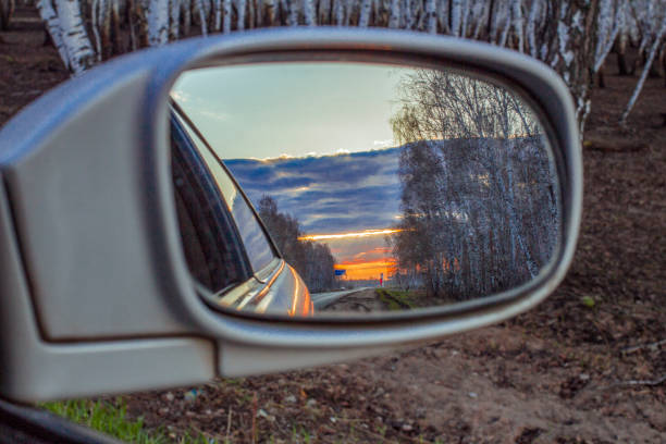 reflexo do sol no retrovisor de um carro em uma estrada. borrão de tiro - rear view mirror car mirror sun - fotografias e filmes do acervo