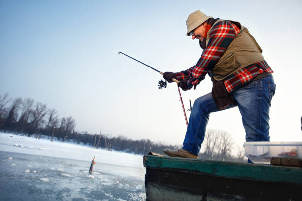 istock Fisherman draws hooked fish from frozen water 960258576