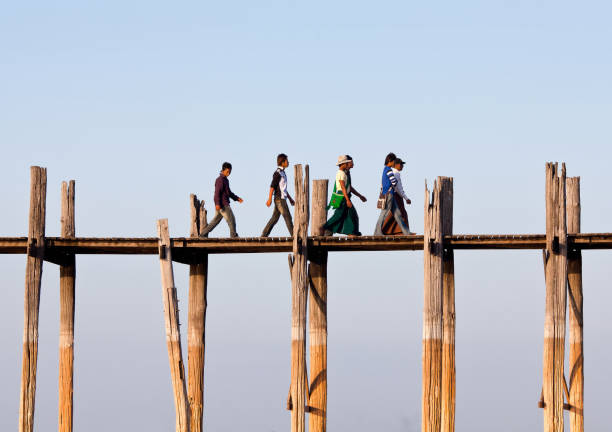 U-Bein teak bridge on Taungthaman lake in Mandalay division, Myanmar Amarapura, Myanmar - January 13, 2011: People walking on famous ancient U-Bein teak bridge on Taungthaman lake in Mandalay division u bein bridge stock pictures, royalty-free photos & images