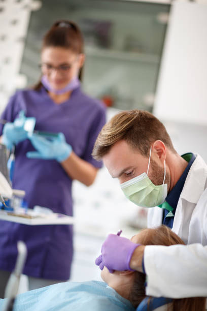 Dentist with assistant working in dental ambulant with patient Male dentist with female dental assistant working with patient in dental ambulant ambulant patient stock pictures, royalty-free photos & images