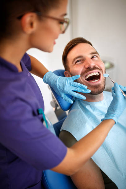 istock Female dentist with dental mirror looking patient’s teeth 960268680