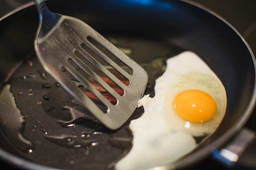 Close-up of an egg being fried. Going to be picked out with the spatula.