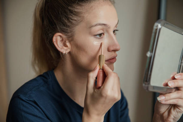 Applying Make-up to Under her Eyes Close-up, side view of a young female adult applying make-up. concealer stock pictures, royalty-free photos & images