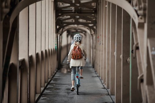 Rear view, wide angle shot of a unrecognisable person cycling to work over a bridge.